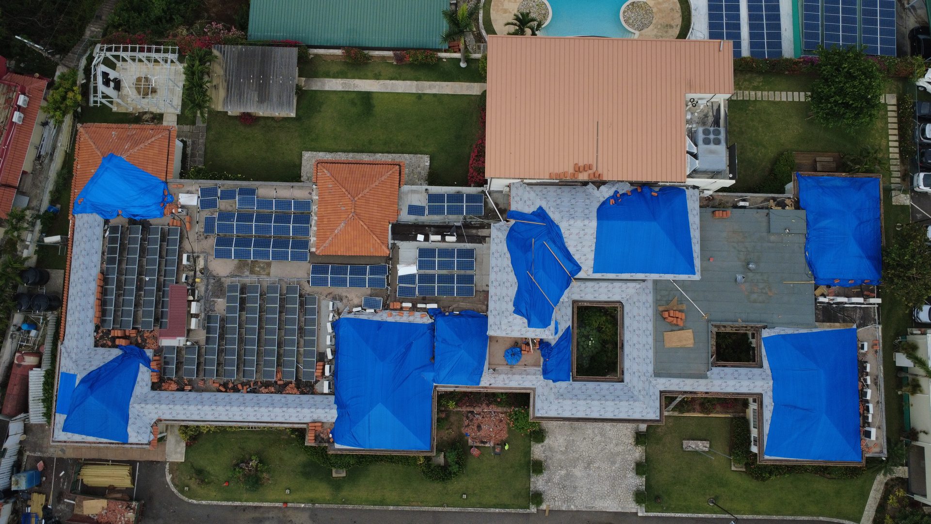 Hurricane damaged roofs under tarpaulin in Jamaica, aerial view