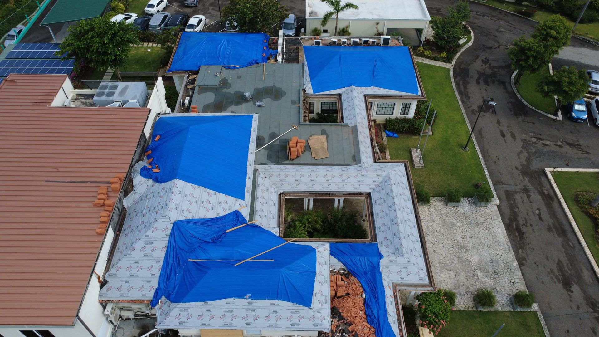 Storm-damaged roofs under blue tarpaulins after a hurricane, Montego Bay