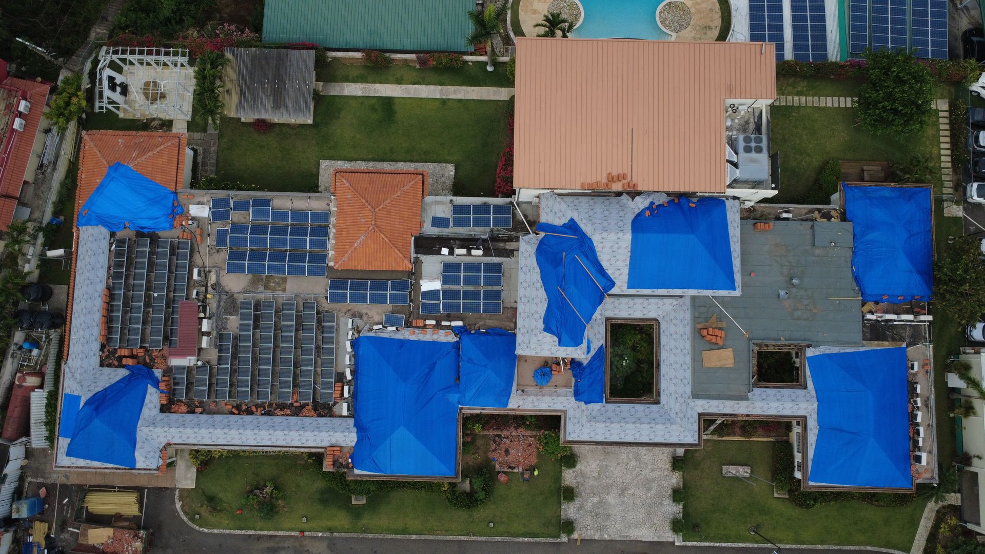 Hurricane-damaged roofs under tarpaulin, aerial view